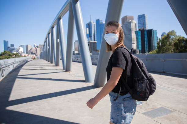 Walking in Melbourne Wearing a Face Mask Young woman wearing a face mask walking through the streets of Melbourne, Australia on a sunny day melbourne street stock pictures, royalty-free photos & images