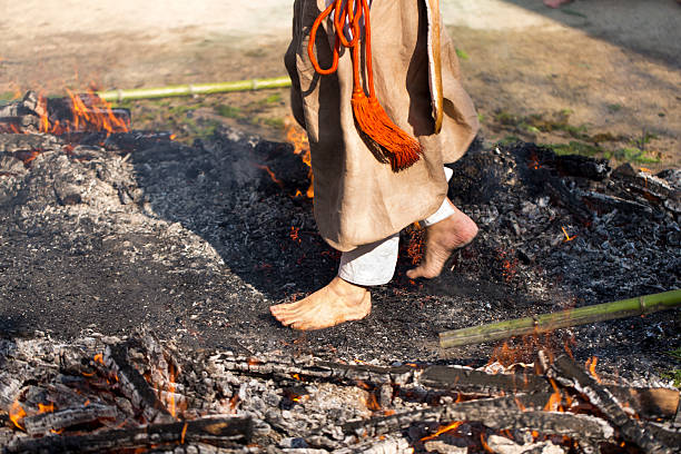 Walking on Hot Coals at Fire Festival Fukuoka, Japan - December 5, 2013: The largest annual event at Atago Shrine in Fukuoka, Japan is the Fire Festival. By burning written prayers in a bonfire, and walking barefoot across burning coals, shrine patrons can purify themselves and stave off misfortune. Here, a believer walks barefoot across the hot coals. firewalking stock pictures, royalty-free photos & images