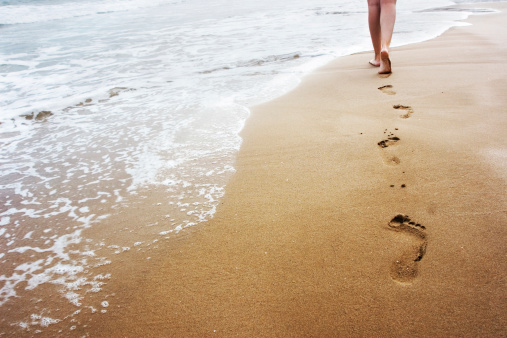 A young woman walking on the sand.