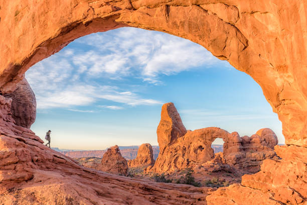 Walking Through a Window A woman walks through North Window Arch with Turret Arch in the background arches national park stock pictures, royalty-free photos & images