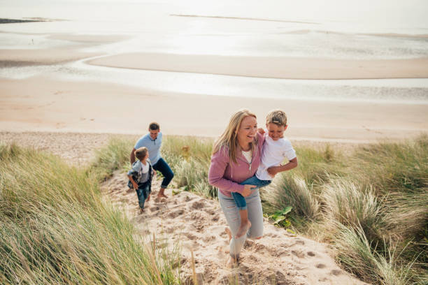 Walking up the Sand Dune HIgh angle view of a family walking up the sand dune from the beach. northumberland stock pictures, royalty-free photos & images