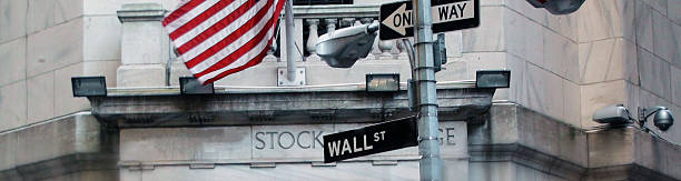 wall street señal con nosotros bandera en la ciudad de nueva york - nyse fotografías e imágenes de stock