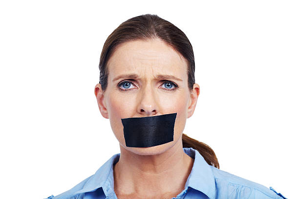 I want to be heard! Portrait of an unhappy woman with black tape stuck across her mouth - conceptual human mouth gag adhesive tape women stock pictures, royalty-free photos & images