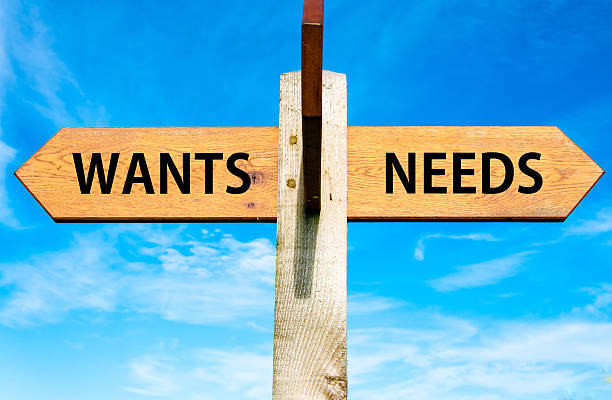Wants versus Needs messages, Consumerism conceptual image Wooden signpost with two opposite arrows over clear blue sky, Wants versus Needs messages, Consumerism conceptual image wanted signal stock pictures, royalty-free photos & images