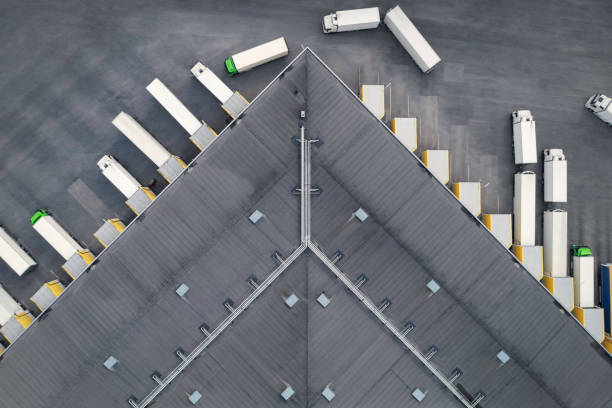 Warehouse distribution Aerial view of a large distribution warehouse with loading docks and many trucks. freight transportation stock pictures, royalty-free photos & images