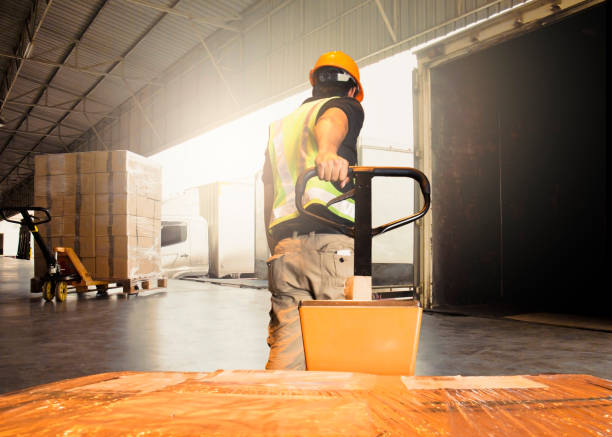 warehouse worker unloading pallet shipment goods into a truck container - forklift imagens e fotografias de stock