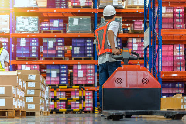 Warehouse Worker with Hand Truck. Warehouse worker walking among shelves with hand truck in to large storage room. push cart stock pictures, royalty-free photos & images