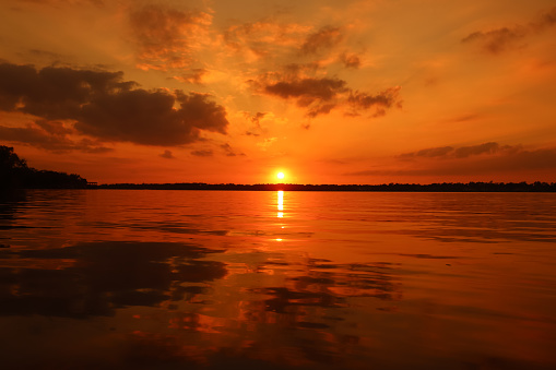 Amber and bronze colored sundown reflection warm hues on the water's surface.
