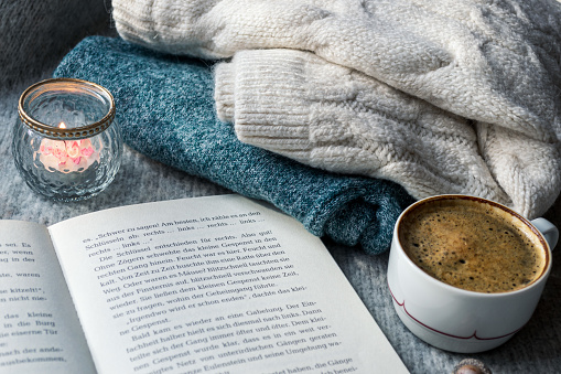 Warm knitted sweater and hot black coffee for a cozy evening reading a book