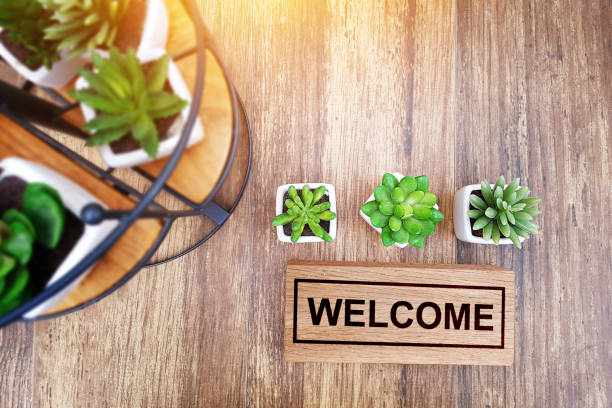 warm welcome sign for business concept. wooden welcome sign on table decorate with little cactus and copy space for your text, top view with yellow light to make warm feeling stock photo