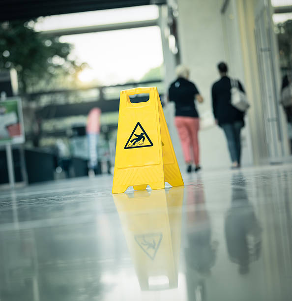 Warning sign slippery A yellow warning sign "slippery " with walking people in the background slip and fall stock pictures, royalty-free photos & images