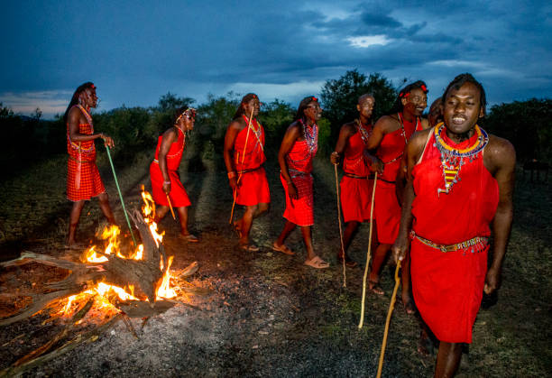 Warriors the Masai tribe dancing ritual dance around the fire late in the evening. Warriors the Masai tribe dancing ritual dance around the fire late in the evening. Kenya, Masai Mara, September 22, 2015 masai warrior stock pictures, royalty-free photos & images