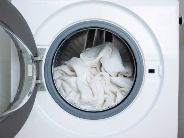 Wash white clothes. White towels inside the open washing machine. Sanitize the laundry. stock photo