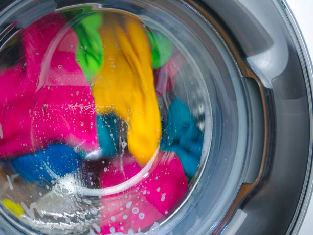 washing colored laundry in the washing machine with detergent for colored clothes, washing machine door closed during washing stock photo