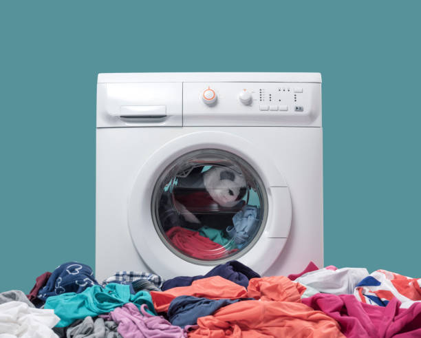 Washing machine and heap of dirty clothes stock photo