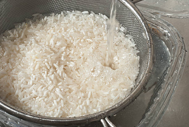 Washing with fresh water white rice in the sink stock photo