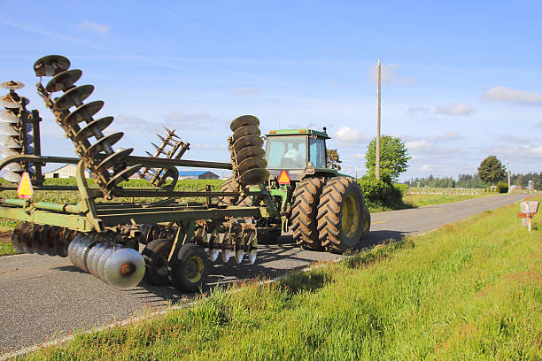 Washington Farmer Transporting Plow A Washington farmer drives his tractor while transporting his plow on a rural road.   agricultural equipment stock pictures, royalty-free photos & images