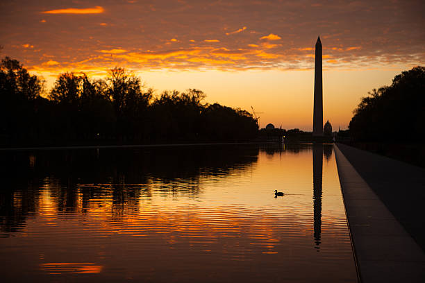 Washington Monument silhouetted at sunrise with reflection. stock photo