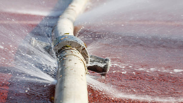 wasting water - water leaking from hole in a hose stock photo