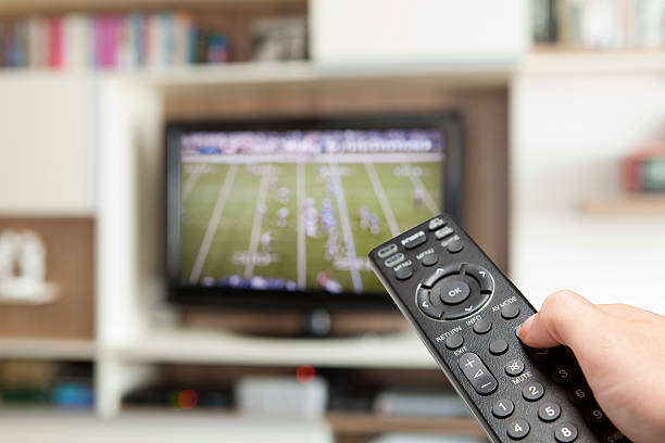 watching football with TV remote control in hand stock photo