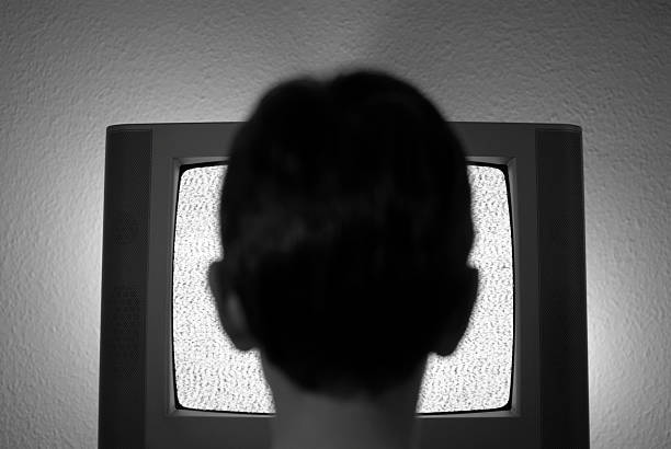 Watching static Boy watching static on a television screen.  ghost boy stock pictures, royalty-free photos & images