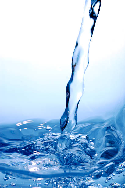 Water being poured into a moving blue water surface stock photo