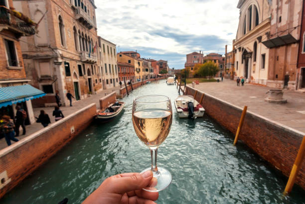 Water canals in Venice and white wine glass in hand of happy tourist stock photo