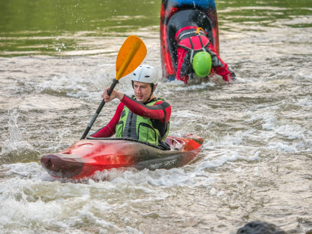 Water canoeing, extreme kayaking Jozefow, Poland - May  12, 2018: Water canoeing, extreme kayaking. Kayakers  in a small sport kayaks are practicing  an approach to a cascade on the Swider River in Poland capsizing stock pictures, royalty-free photos & images