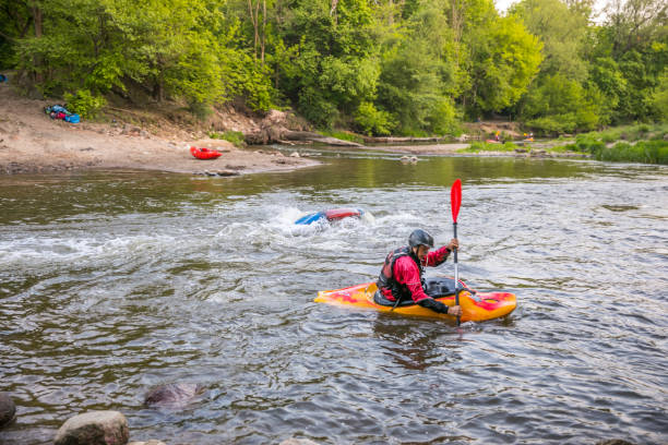 Water canoeing, extreme kayaking Jozefow, Poland - May  12, 2018: Water canoeing, extreme kayaking. Kayakers  in a small sport kayaks are practicing  an approach to a cascade on the Swider River in Poland capsizing stock pictures, royalty-free photos & images