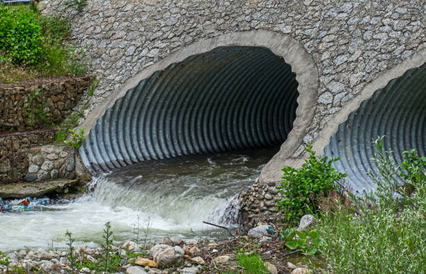 Water drains through pipes Water drains through pipes, under a bridge. contamination stock pictures, royalty-free photos & images