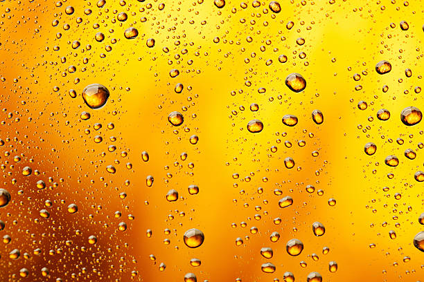 Water drops background "Ice Cold  Glass , covered with water drops - condensation. The background is clear with the emphasis on water drops on yellow-golden background. Close - up. Very shallow DOF, defocused with Canon 90mmTS + 1DS mkIII. The grain and texture added.SEE ALSO:" juice drink photos stock pictures, royalty-free photos & images
