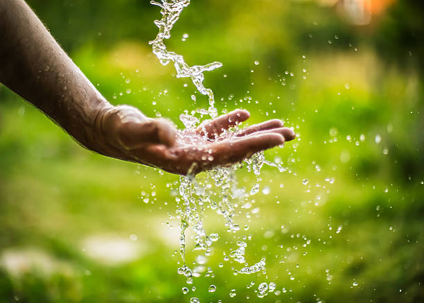 Water falling onto a hand in a field Outstretched hand under the stream of fresh water freshwater stock pictures, royalty-free photos & images