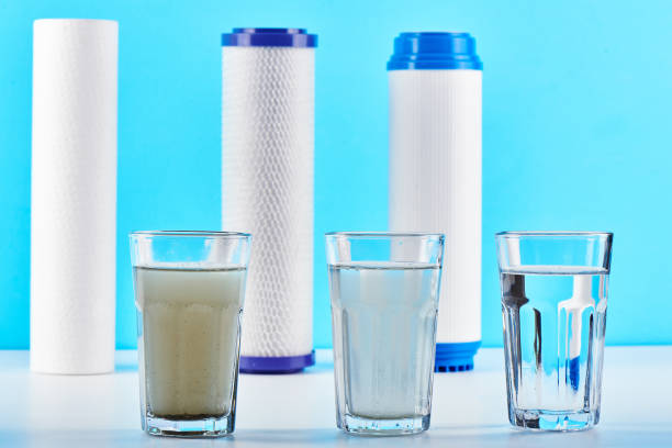 Water filters concept. Carbon cartridges and a three glasses on a white blue background. Household filtration system. stock photo