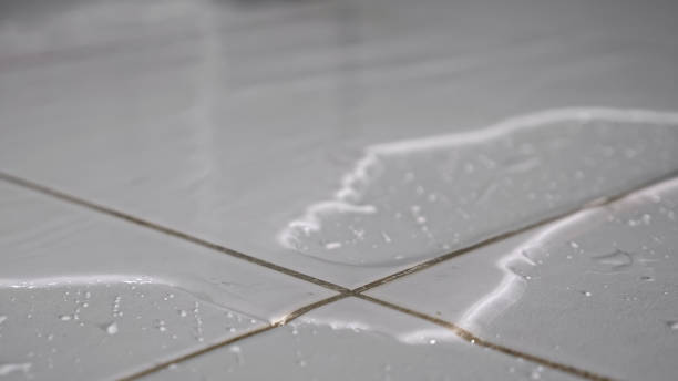 Water flows on floor covering white ceramic tile in bathroom stock photo