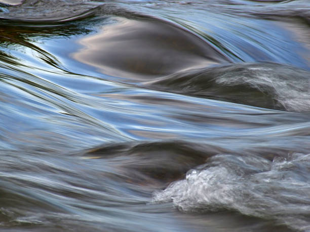 Water in motion Flowing water with the reflection of the blue sky taken with a slow shutter speed rapids river stock pictures, royalty-free photos & images