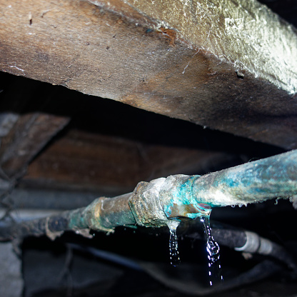 water leak in corroded copper water pipe in the plumbing under a traditional villa bungalow in New Zealand.