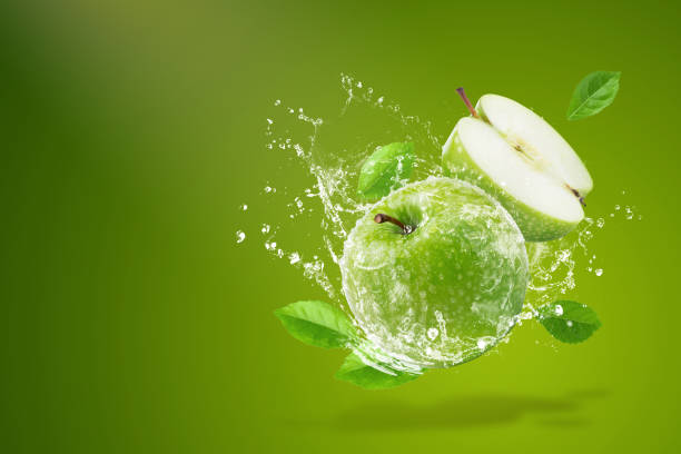 Water splashing on Fresh green apple on Green background stock photo
