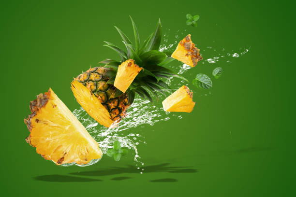 Water Splashing on Fresh Pineapple is tropical fruit isolated on Green background. stock photo