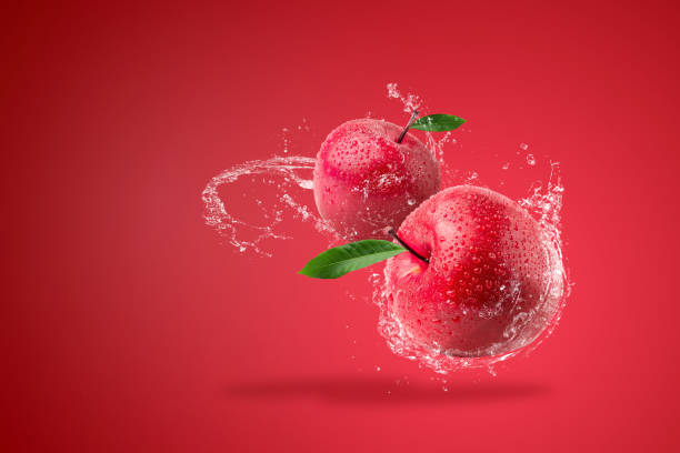 Water splashing on Fresh Red apple on red background. stock photo