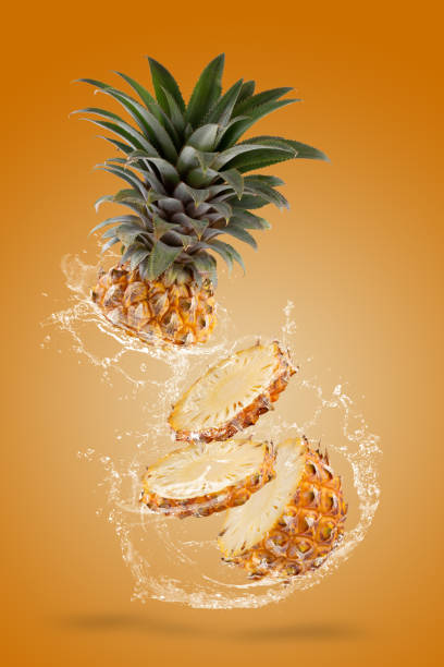 Water Splashing on Split Pineapple Fruit isolated over yellow background. stock photo
