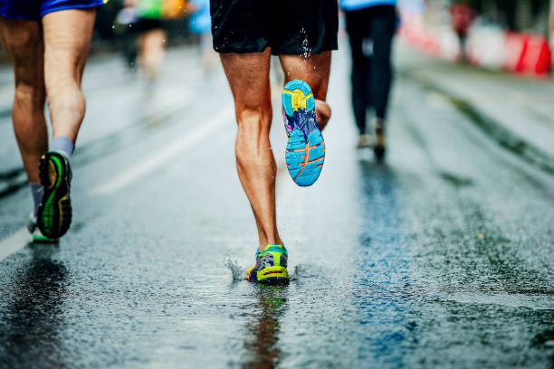 water sprays from under running shoes runner men stock photo