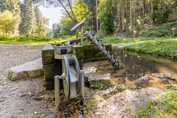Water werk for drawing water from a pond next to a dirt road Water werk for drawing water from a pond next to a dirt road with abundant leafy trees in the background, sunny summer day on Mullerthal Trail, Luxembourg luxembourg benelux stock pictures, royalty-free photos & images