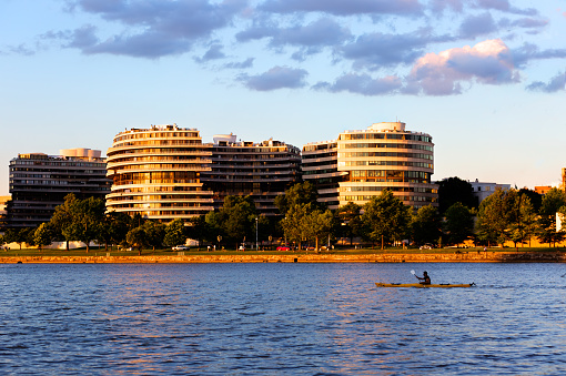 Washington, DC, USA - June 07 2016: Watergate hotel and apartments at golden hour with a Kayak in the Potomac.