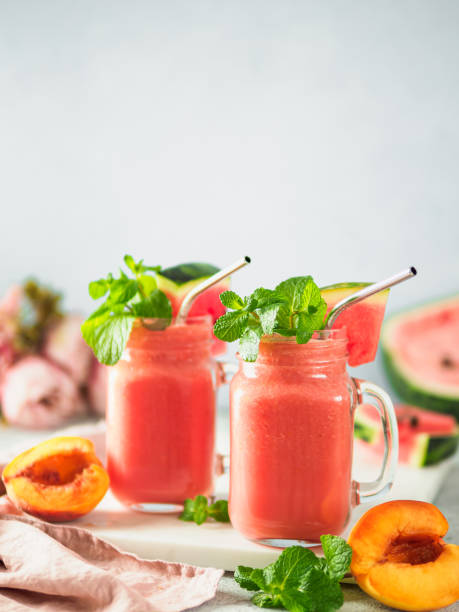 Watermelon and Peach Smoothies, copy space Freshly Blended Watermelon and Peach Smoothies in mason jar and metal straw. Copy space for text or design. Vertical. peach smoothie stock pictures, royalty-free photos & images