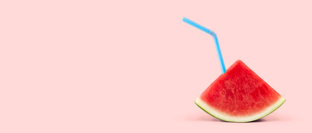 Watermelon Juice on Pink Background Slice of watermelon with blue straw on soft pink background with copy space watermelon juice stock pictures, royalty-free photos & images