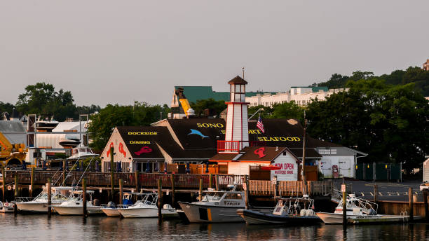 Waterside dinning restaurant with beautiful sunrise light and boats docking in Norwalk river near downtown stock photo