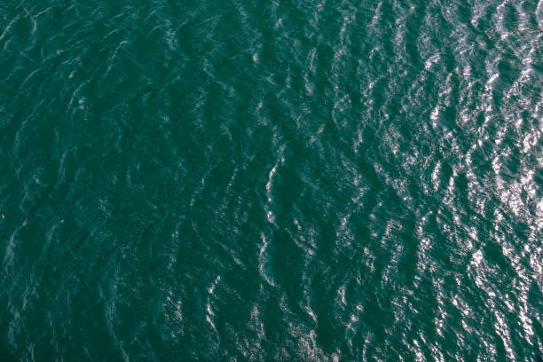 Waves and spray of a lake in the sunlight from above stock photo