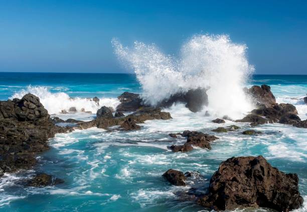 Waves crashing against rocks in ocean stock photo