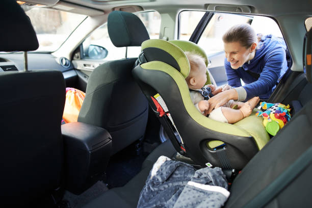 We have some cute and precious cargo onboard this trip Portrait of a mother fastening her baby boy safely in a car seat car safety seat stock pictures, royalty-free photos & images