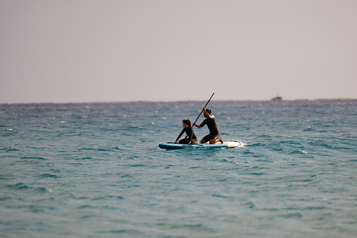 SUP Stand up Surf  young couple with paddle in a blue ocean sea